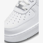 Close-up of Nike Air Force 1 Low Triple White toe box with perforations, white leather texture, stitching, and AF1 lace dubrae.