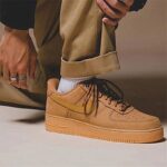 Lifestyle photo of Nike Air Force 1 Low Wheat CJ9179-200 paired with cuffed trousers and streetwear-inspired outfit.