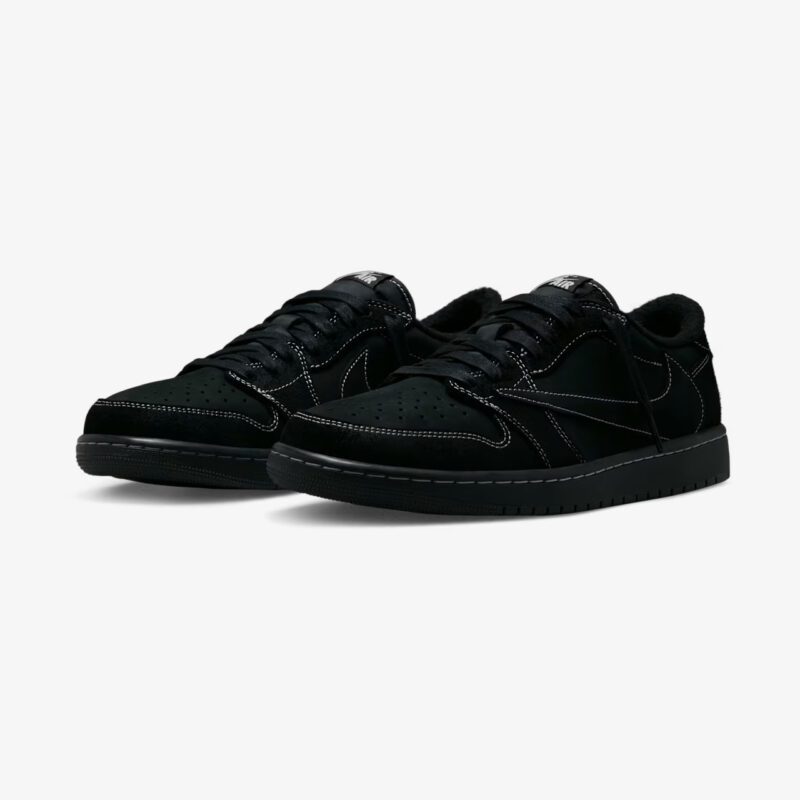 Travis Scott Jordan 1 Low Black Phantom sneakers shown in a front three-quarter view, featuring premium black suede, reverse Swoosh, white contrast stitching, and an all-black sole.